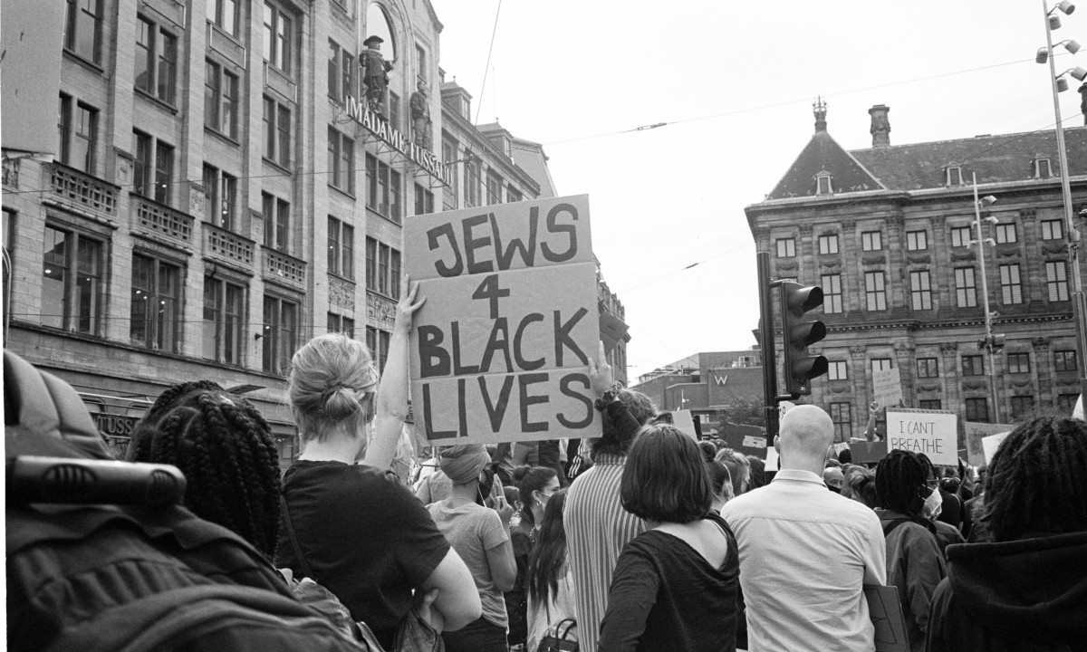 Crowd at a city protest with a person holding a sign reading 'JEWS 4 BLACK LIVES'