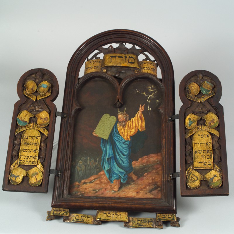 Gemälde von Mose mit zwei Steintafeln und erhobenem Arm, eingerahmt von Türen mit den Stämmen Israels und hebräischen Schriftbändern
