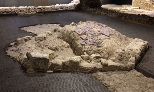 Relikte einer antiken römischen Villa mit Mauerresten und einem Bereich mit roten Fliesenfragmenten im jüdischen Museum Wien