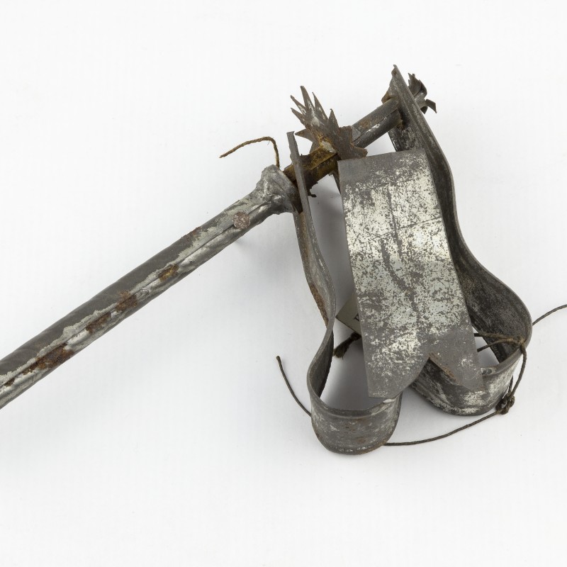 Alter metallischer Handschelle mit einem langen, stacheligen Hebel und einem Metallband, daran befestigte Schnur.