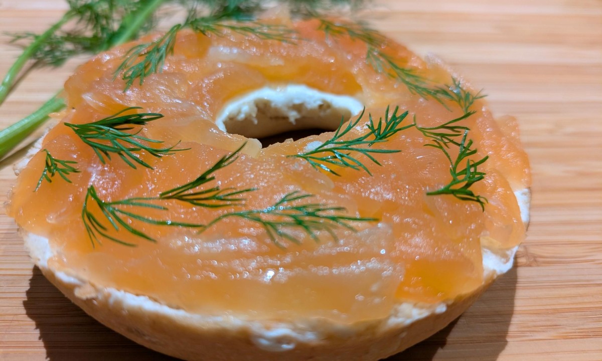 Bagel with cream cheese, smoked salmon, and dill on wooden surface
