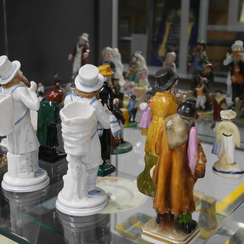 Porzellanfiguren von Menschen in historischen Kleidern, auf Glasregalen im Museum ausgestellt