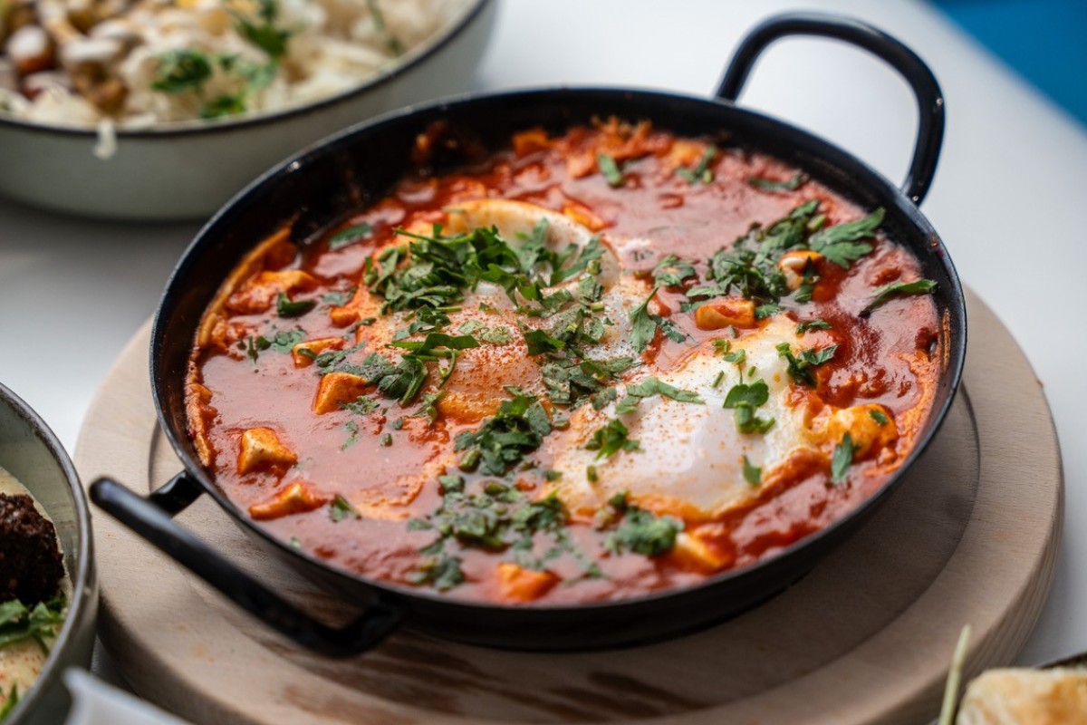 Shakshuka in Pfanne: Schwarze Pfanne mit Shakshuka, Tomatensoße, pochierten Eiern und gehacktem Koriander