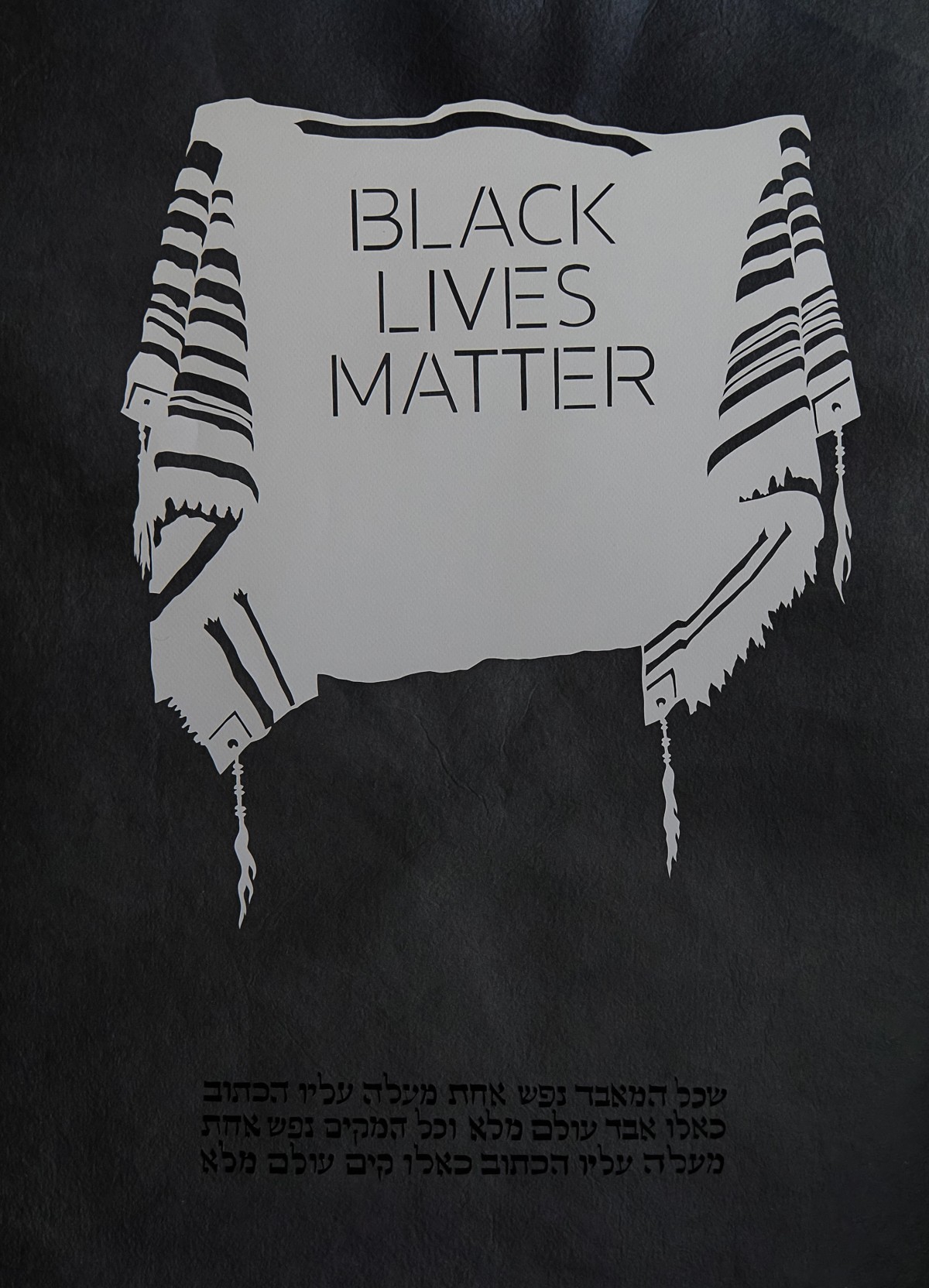 Tallit with 'BLACK LIVES MATTER' text: A white tallit with black stripes displaying the text 'BLACK LIVES MATTER'. Hebrew text in black is below.
