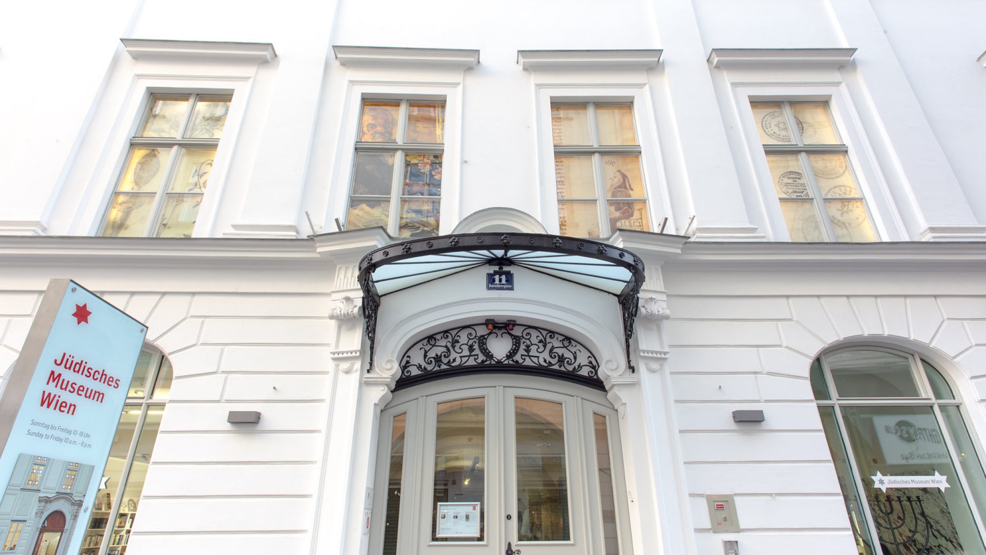 Eingang des Jüdischen Museums Wien: Eingangsbereich des Jüdischen Museums Wien mit Weißer Fassade, großen Fenstern und einem beschrifteten blauen Schild links