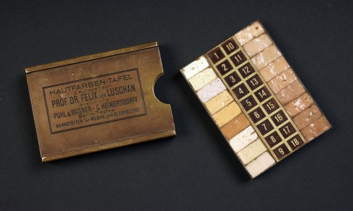 Kleine rechteckige Metallbox mit Aufschrift und herausgenommenes Tablett mit 18 Hautfarbmustern in verschiedenen Beige- und Brauntönen
