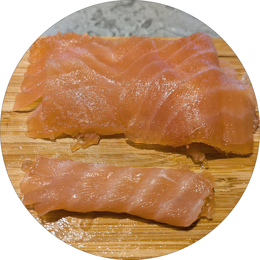 Two pieces of graved salmon on a wooden board